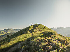 Ein Hügel vor einer Berglandschaft mit einer Familie darauf.