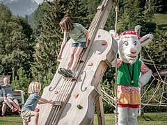 Das Maskottchen Saani steht neben einer überdimensionalen Geige