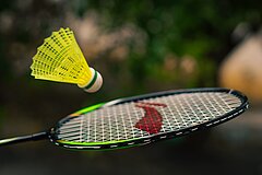 Ein Badminton Schläger mit einem Federball in der Luft.