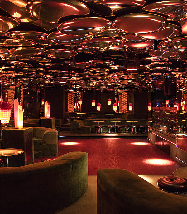 Stilvoller Club mit roten Leuchten, verspiegelten Wänden und Lounge-Bereichen im GreenGo des Gstaad Palace.