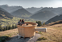 A couple sits in a giant wooden caquelon and enjoys a fondue and the view.