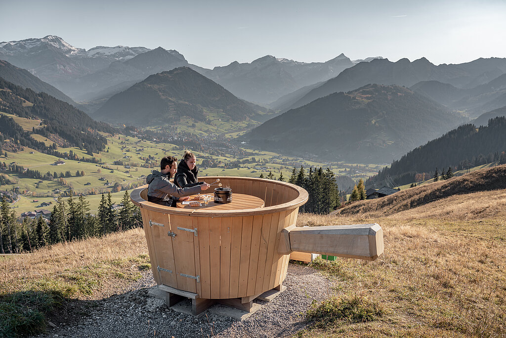 <p>A couple sits in a giant wooden caquelon and enjoys a fondue and the view.</p>