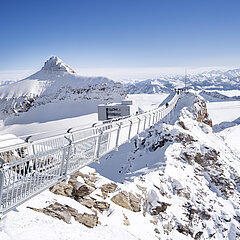  Photo de haute montagne avec vue sur les sommets enneigés et le Peak Walk, le pont suspendu qui relie deux sommets. 