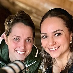 Zwei lächelnde junge Frauen vor einem Mikrofon.