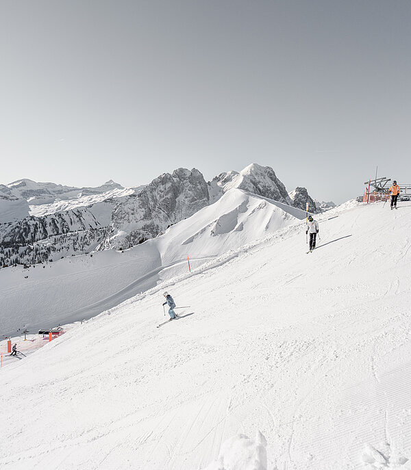 Verschneite Skipiste der La Videmanette mit mehreren Skifahrern vor alpiner Bergkulisse. 