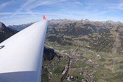 Aussicht von einem weissen Flugzeug auf das grüne und bergige Saanenland.