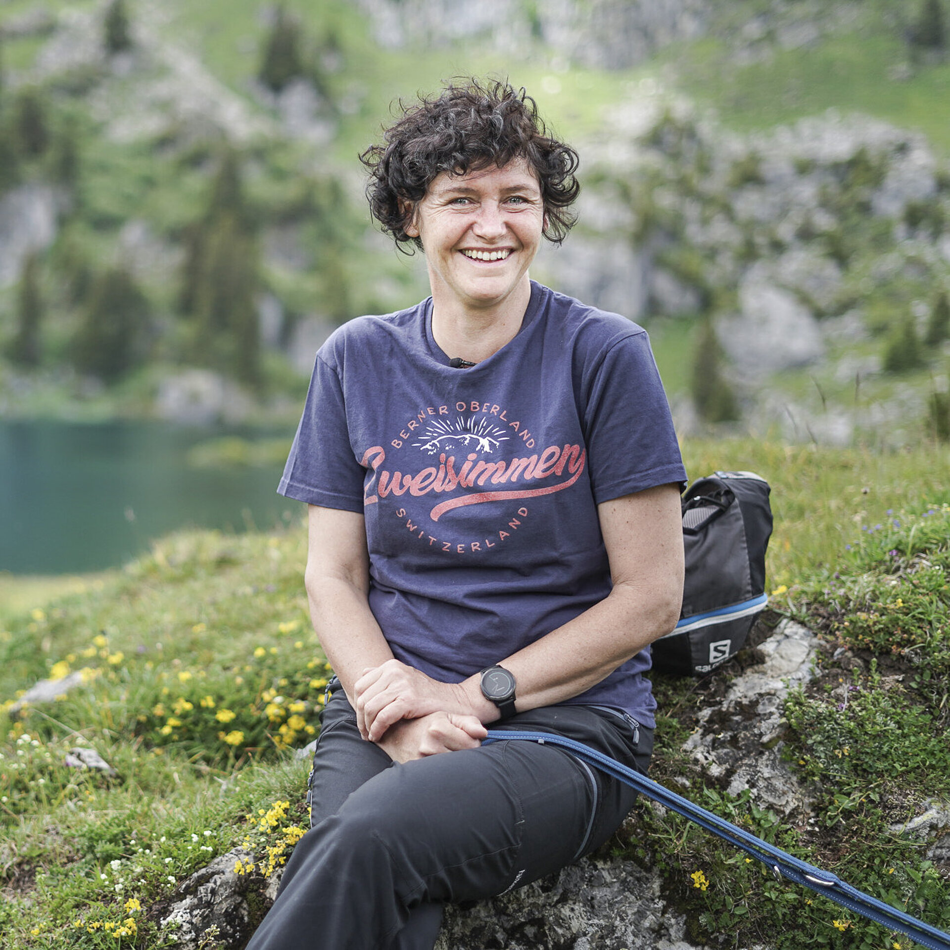 Dame in einem dunklen T-Shirt mit Aufdruck, sitzt auf einem Stein beim Seebergsee.